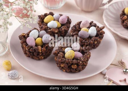 Food, Sweet and tasty Easter chocolate rice nest cake with mini candy eggs, creative recipe for Easter table. Pink background Stock Photo