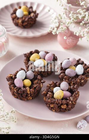 Food, Easter chocolate rice nest cake with mini candy eggs, creative recipe for Easter table. Pink background Stock Photo