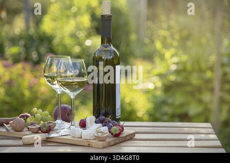 Food, Two glasses of wine with fruits and cheese for romantic outdoor picnic in summer garden Stock Photo