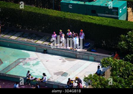 Zoomed shot of crowd of people playing hindu holi festival of colors on side of empty swimming pool enjoying the onset of summer Stock Photo