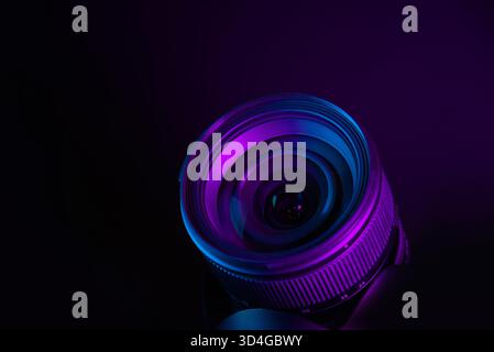 Modern camera lens under purple and blue lighting, futuristic photography equipment background Stock Photo