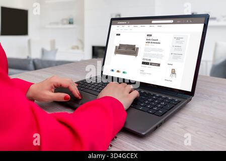 Woman browsing online furniture store on laptop, shopping for sofa couch through e-commerce website, modern home interior and online retail concept Stock Photo