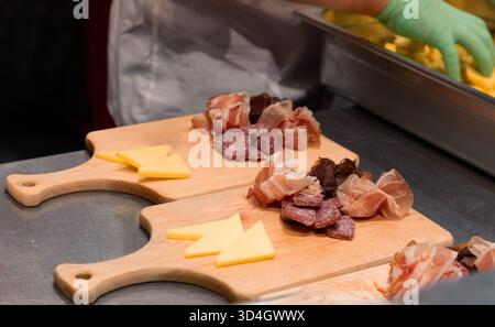 potbelly pig. Assorted meats and cheeses are beautifully arranged on wooden cutting boards in a kitchen setting, showcasing culinary artistry Stock Photo
