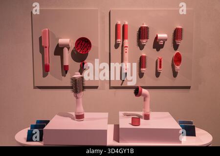 Modern hair styling tools are showcased on minimalist wall panels, featuring various designs and colors, creating a stylish and organized display. Stock Photo