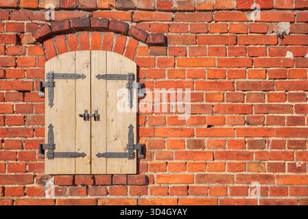 Old brick wall with new wooden shutters. Stock Photo