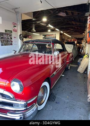 Red 1950s Pontiac convertible in auto upholstery workshop, California Stock Photo