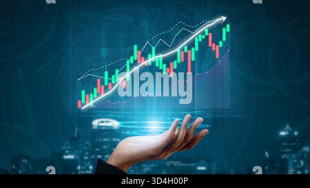 A hand holds a glowing financial graph with rising trend indicators and colorful candlestick animations, set against an urban night backdrop Stock Photo