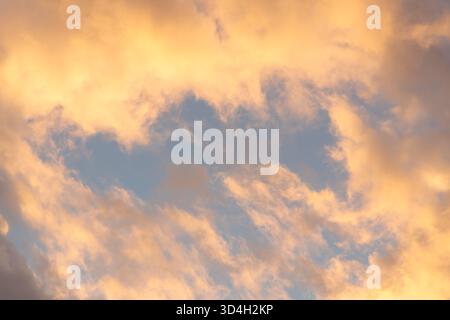 Warm orange clouds illuminated by setting sun in the Netherlands. A glowing evening sky creates a peaceful atmosphere with golden hues and soft light Stock Photo
