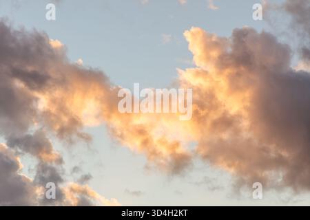 Soft pastel-colored clouds in the evening sky illuminated by warm sunlight over the Netherlands. Tranquil and atmospheric nature scene Stock Photo