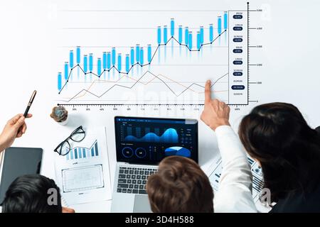 A dynamic business meeting scene showcasing professionals analyzing data trends and charts using technology, emphasizing teamwork and strategic Stock Photo