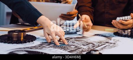 A group of engineers collaborates on technical drawings, analyzing components and specifications. They focus on creativity and precision in a Stock Photo