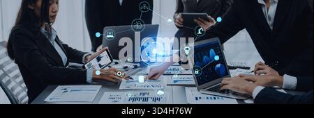 A team of professionals engages in a collaborative meeting in a modern office, analyzing data and sharing insights using various digital devices for Stock Photo