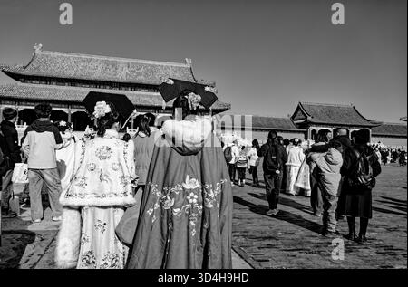 Inside the Forbidden City — black-and-white view of visitors in embroidered winter hanfu crossing a courtyard Stock Photo