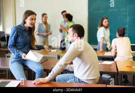 Man and woman students having small talk in classroom Stock Photo