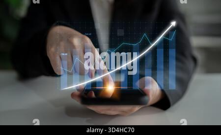 Professional person interacts with smartphone displaying financial data and growth trends, emphasizing the importance of analytics in contemporary Stock Photo