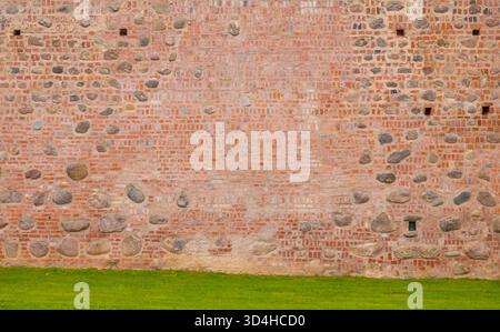 an ancient wall made in the middle ages of stones, cobblestones and red brick, details of an ancient castle Stock Photo