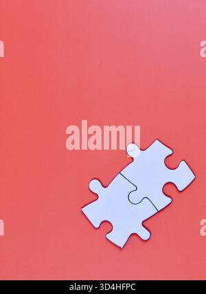 Two interlocked white puzzle pieces on orange background, symbolizing connection, unity, or problem-solving in a minimal visual composition. Stock Photo