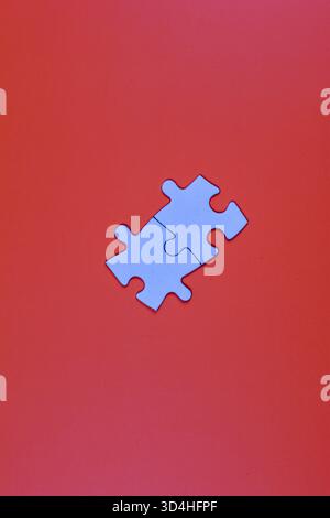 Two interlocked white puzzle pieces on orange background, symbolizing connection, unity, or problem-solving in a minimal visual composition. Stock Photo