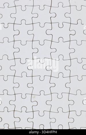 Blank interlocked jigsaw puzzle pieces arranged in grid pattern; uniform white surface emphasizes shape-based assembly challenge without visual cues. Stock Photo