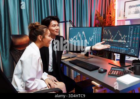Asian businessman showing dynamic stock exchange currency rate statistic online to share with coworker, explaining to compare with high or low on Stock Photo