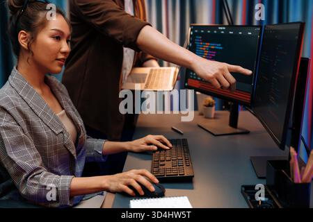 Serious of IT developers discussing intelligent website development coder system running data online two screens with laptop showing information Stock Photo