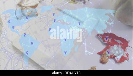 Showing translucent map across desk, displaying network lines, purple pins, notepad, red leaf, nut Stock Photo
