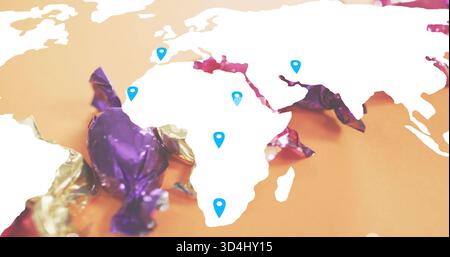 Displaying white map cutout centered on orange tabletop, showing blue pins and purple gold wrappers Stock Photo