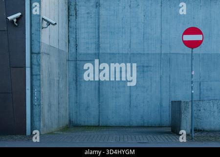 No entry road sign and CCTV cameras on a modern concrete wall. Stock Photo