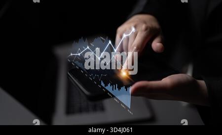 A professional hand interacts with a sleek smartphone displaying dynamic financial graphs and analytics, symbolizing data-driven decision making and Stock Photo