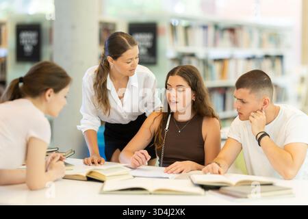 Friendly group of students prepare for classes and exams by studying together in university library Stock Photo