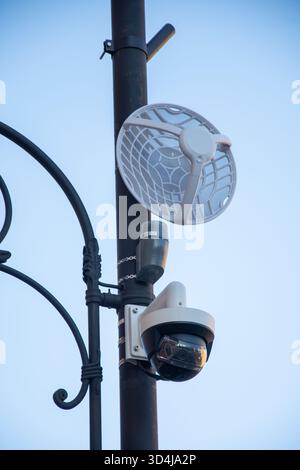 combination of a security camera and a wireless networking device mounted on a pole. The lower device is a closed-circuit television (CCTV) camera use Stock Photo
