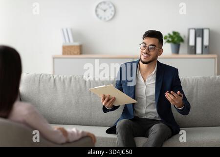 Middle Eastern Counselor Provides Support to Female Client During Psychotherapy Session in Office Stock Photo