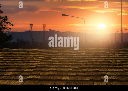 Wooden roof tiles glowing under warm sunlight during sunset with communication towers and hills in background. Natural texture, architectural detail, Stock Photo
