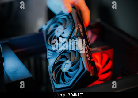Installing a video card on the motherboard. The technician installs computer components in a open PC case. PC assembly and modernization. Stock Photo