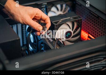 Installing a video card on the motherboard. The technician installs computer components in a open PC case. PC assembly and modernization. Stock Photo