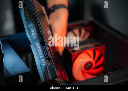 Installing a video card on the motherboard. The technician installs computer components in a open PC case. PC assembly and modernization. Stock Photo