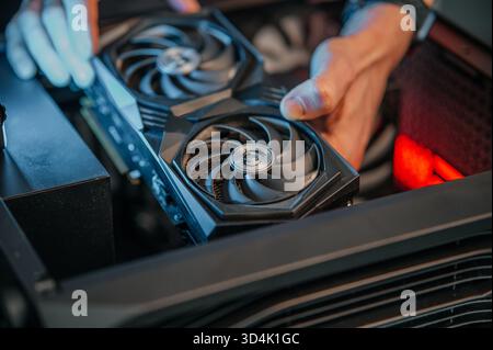 Installing a video card on the motherboard. The technician installs computer components in a open PC case. PC assembly and modernization. Stock Photo