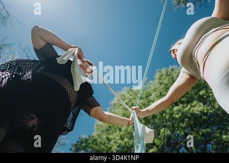 Two women playing with ribbons in a sunny park setting viewed from below Stock Photo
