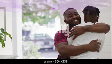 Embracing father and son in home entryway, wearing plaid shirt and white T-shirt, near open doorway Stock Photo