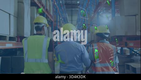 Walking warehouse team checking pallet racks in long aisle wearing yellow helmets and vests with AR Stock Photo