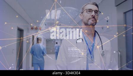 Walking mature male physician progressing down hospital corridor, lab coat and digital overlay Stock Photo