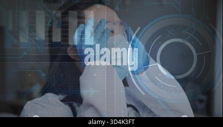 Rubbing Korean doctor covering eyes in clinic showing lab coat stethoscope mask goggles gloves HUD Stock Photo