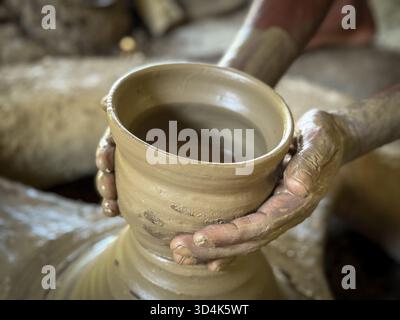 Close-up of artisan hands shaping a clay pot on a traditional pottery wheel in rural Bangladesh. Authentic craftsmanship showcasing cultural heritage Stock Photo