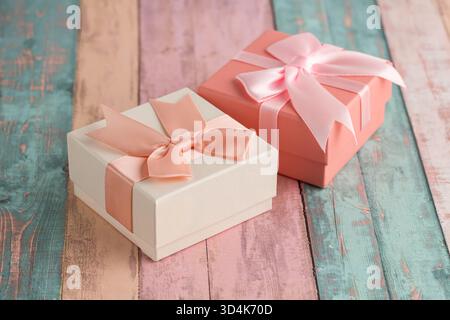 Two gift boxes with ribbons on colorful wooden background. Stock Photo