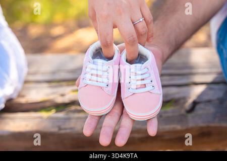 Close up of couple holding pink baby shoes together expecting a daughter Stock Photo