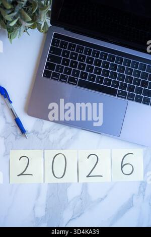 Workspace flat lay with laptop, pen, and 2026 on sticky notes for new year planning Stock Photo