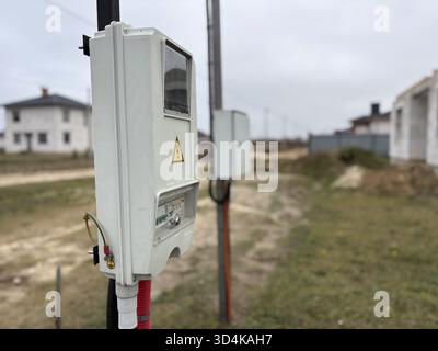The closed electrical box is located on a pole near a house in a private development area. The process of supplying electricity to a new construction Stock Photo
