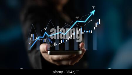 A business professional presents a smartphone displaying dynamic financial graphs, symbolizing data-driven growth and insightful analysis in a Stock Photo