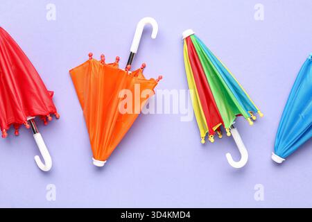 Mini stylish umbrellas on lilac background Stock Photo