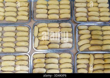 Peeled and sliced fresh cultivated bananas prepared on drying rack for traditional preservation or snack and food processing industry Stock Photo